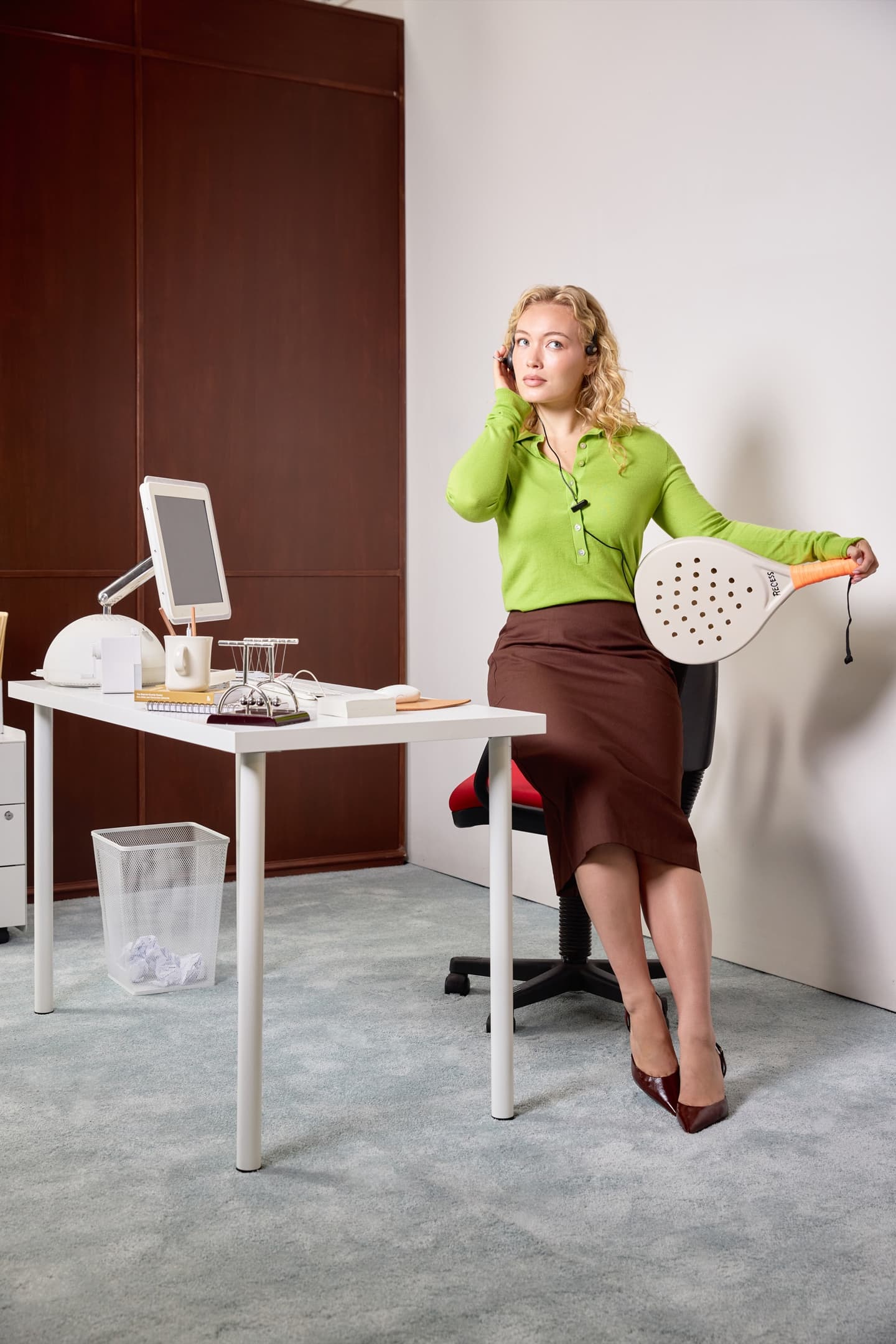 Woman in the office, zoned out on a call with a padel racket by her side